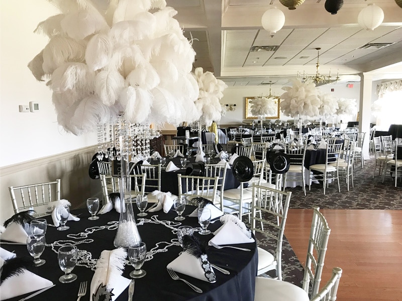 The golf club banquet hall at Copper Hill Country Club decorated with black tab tablecloths and white napkins and centerpieces for a large party.